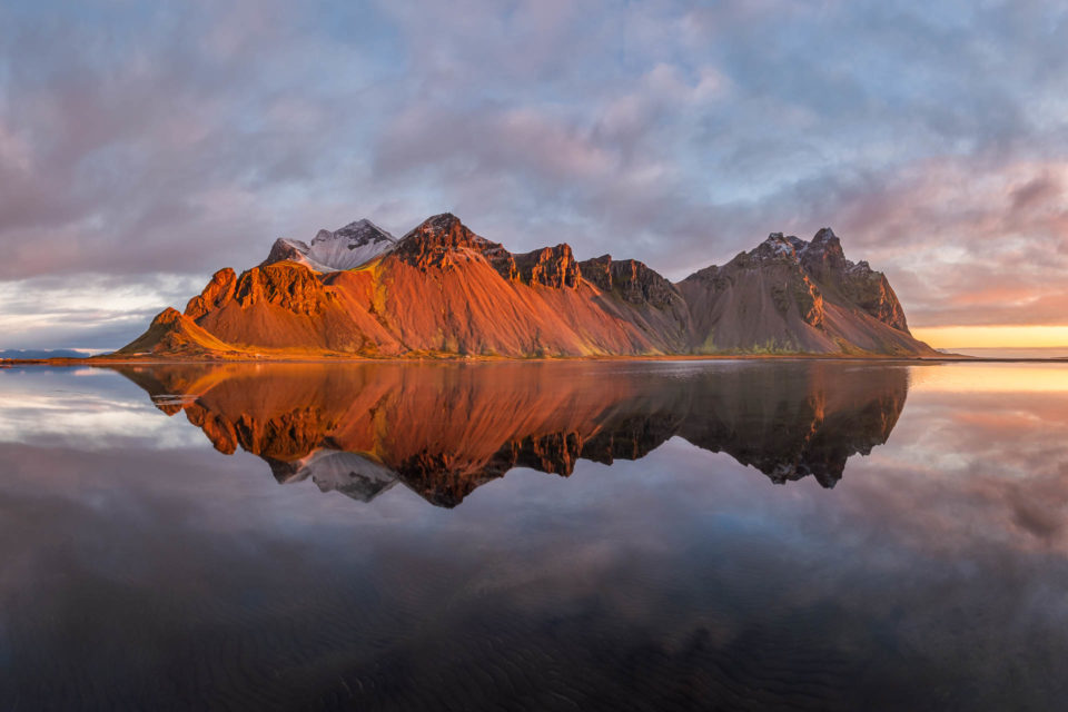 Reflection of Vestrahorn mountain in Iceland at colorful sunrise